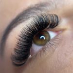 Detailed close-up of a woman's eye with styled eyelashes and groomed eyebrow.